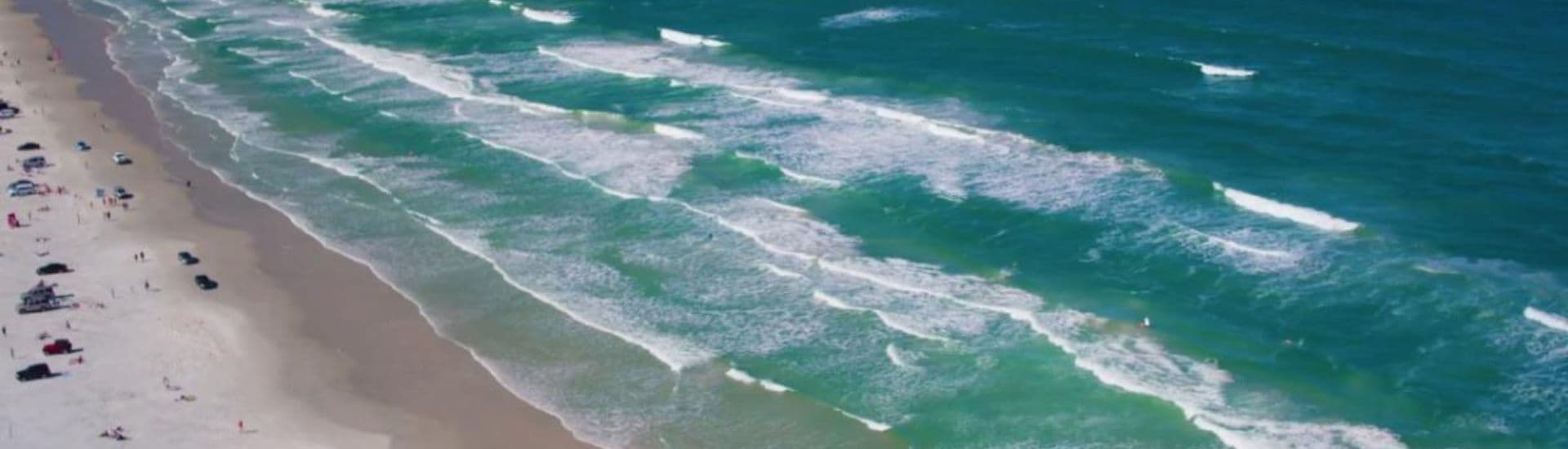 Aerial view of a beach with sandy shores and gentle ocean waves.